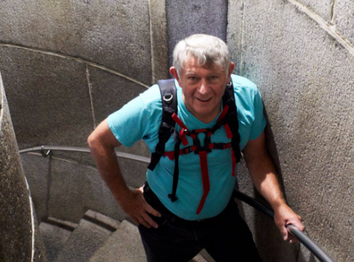 Pat Adamson is pictured in a blue short-sleeve shirt while climbing up Castle circular stone stairs while in Ireland.